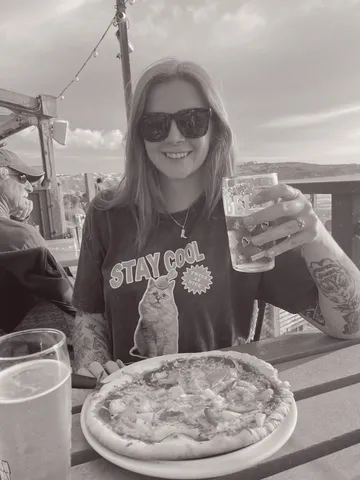 Abby at waterfront restaurant with drink and pizza