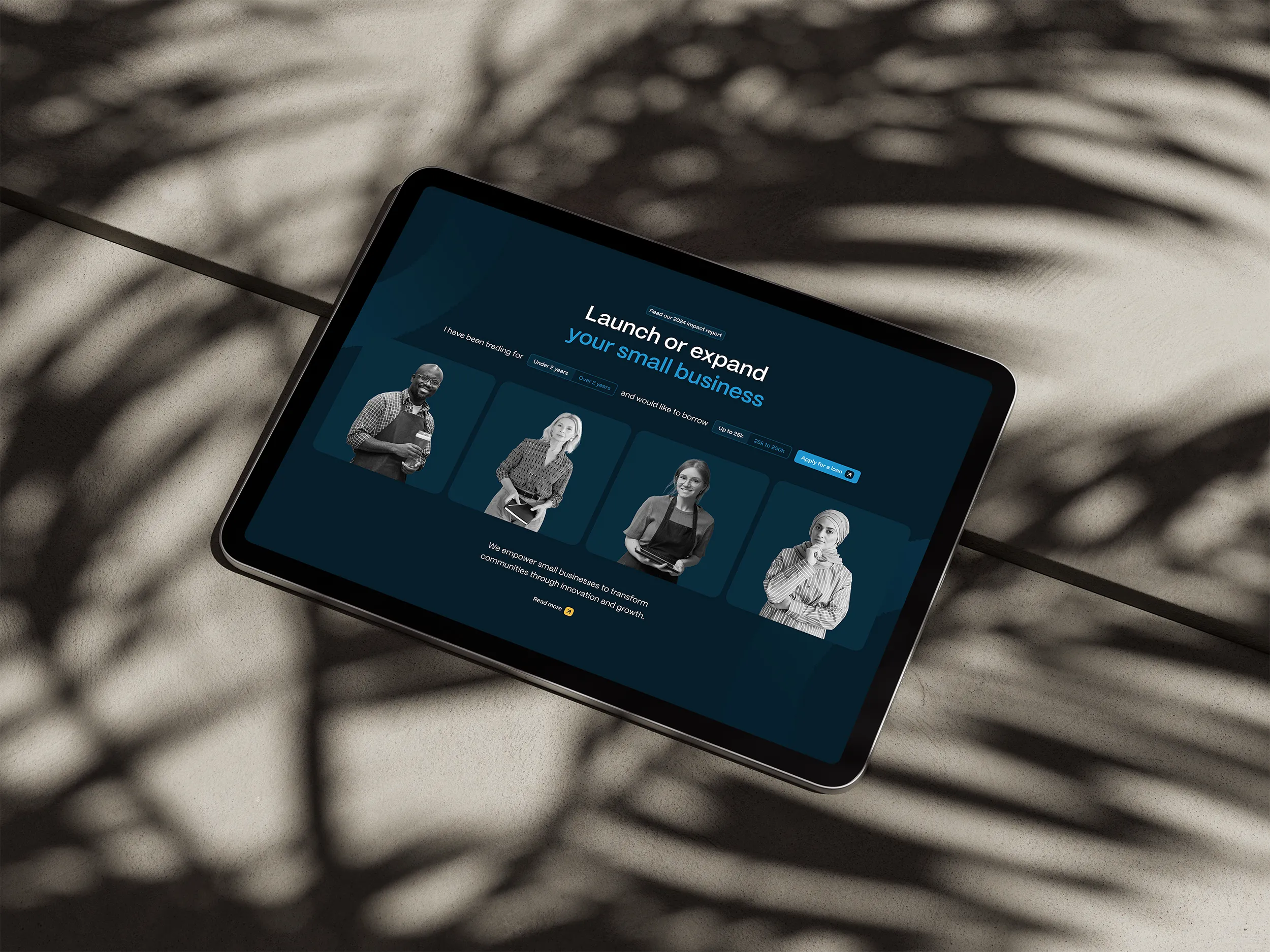 Tablet showing a small business loan website with diverse entrepreneur portraits