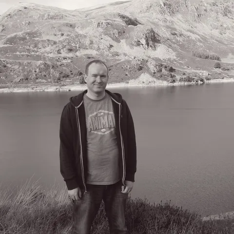 Steven by lake with mountains reflected in water