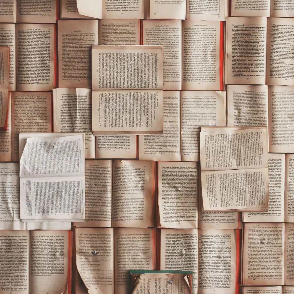 Lots of books with there pages open, laid on top of each other